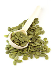 green pumpkin seeds with a wooden spoon