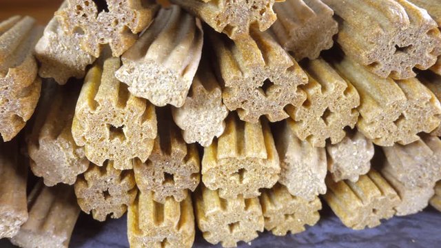Close circular dolly shot of corn and wheat based dog dental chews (for cleaning teeth) in a pile.