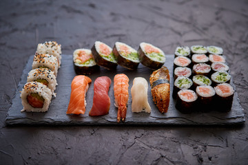 Sushi rolls set with salmon and tuna fish served on black stone board