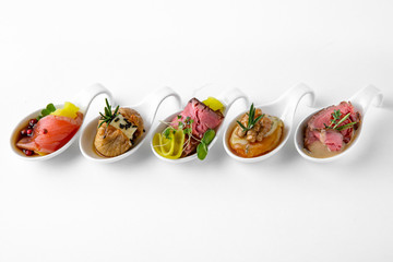Assorted portions of different salmon, dried fruit, cold cuts and cheese snacks. Beautifully decorated catering banquet menu. Food snacks and appetizers for buffet. Isolated on white background