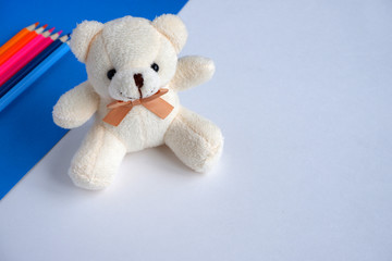 Beautiful beige  bear, colored pencils on a blue and white background. Soft toy. School supplies.  Suitable for advertising backgrounds and greeting cards