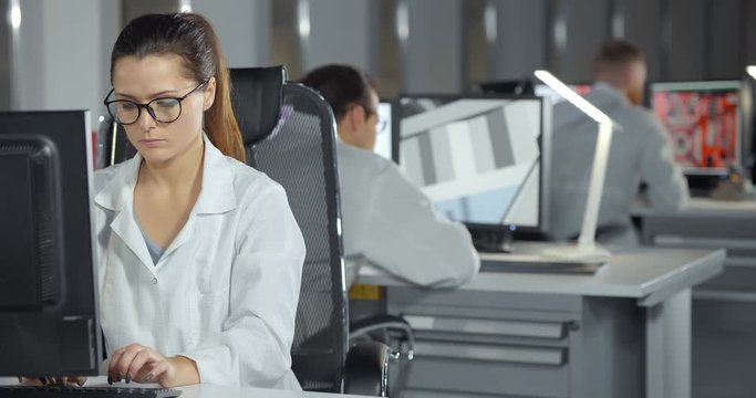 Engineers in white coats using computers in office