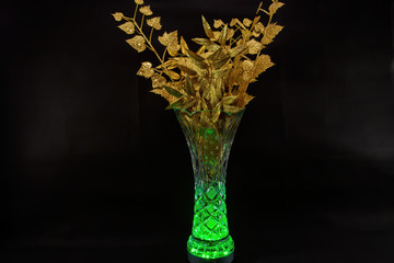 Golden leaves in a vase with lights on a black background