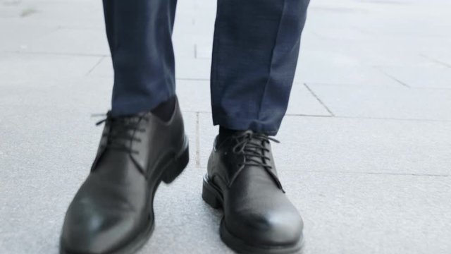 Businessman legs walking on city street.Entrepreneur wearing black leather shoes