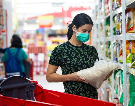 Alarmed Female Wears Medical Mask Against Coronavirus While Grocery Shopping In Supermarket Or Store- Health, Safety And Pandemic Concept - Young Woman Stockpiling Food In Fear Of Covid-19