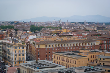 Obraz premium View of the city from a height. Panorama of Rome, Italy on a cloudy day. Mountain silhouettes on the horizon.
