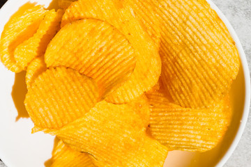 potato crisps served in a white bowl, beer snacks on a on gray background. Fast food, junk-food, cuisine and unhealthy eating concept