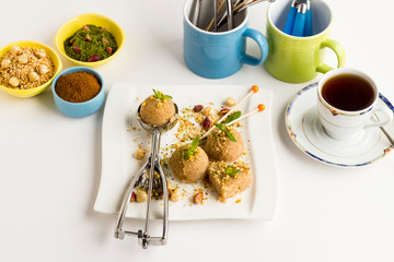 Classic Turkish Dessert,Semolina Halvah,served with a cup of tea on the white surface and nuts.