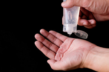 Selective focus of Asian men hand using Alcohol gel, hand sanitizer for personal hygiene on black background to protect, prevent from virus and illness during Corona virus outbreak or Covid 2019.