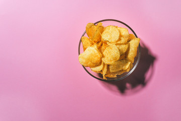 Obraz na płótnie Canvas top view of a bowl full of potato chips pink pastel background. space for text for space copy space