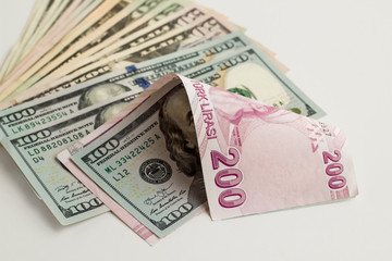 Pile of American Dollars and two hundred Turkish banknote backward curved on white surface with copy space.