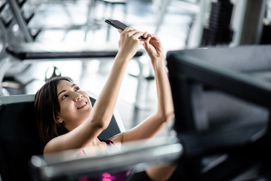 Young asian healthy woman working out and take a selfie in the gym. Exercise, workout, muscle training, weight lifting, weight loss, heart rate practice and diet concept.