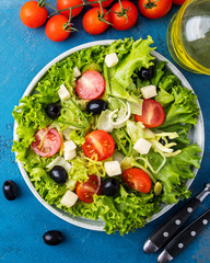 Top view of dieting healthy salad on a plate. Lettuce, cheese, olives, onion and cherry tomatoes. Concept of  healthy vegetarian meal.