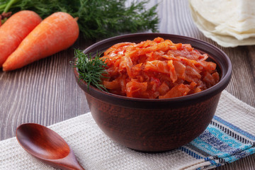 Braised cabbage with tomatoes on an old wooden background in rustic style