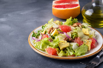 Tasty fruit salad with garpefruit, cheese, lettuce and walnut on a plate. Vitamin salad. Text space