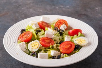 Salad with fresh vegetables: tomatoes, quail eggs, lettuce,  cheese and black olives. Diet and healthy  food concept.