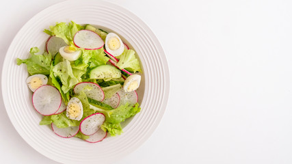 Cucumbers, quaill eggs,  radish and lettuce on a plate. Fresh vegetables salad isolated on white background. Copy space. Top view
