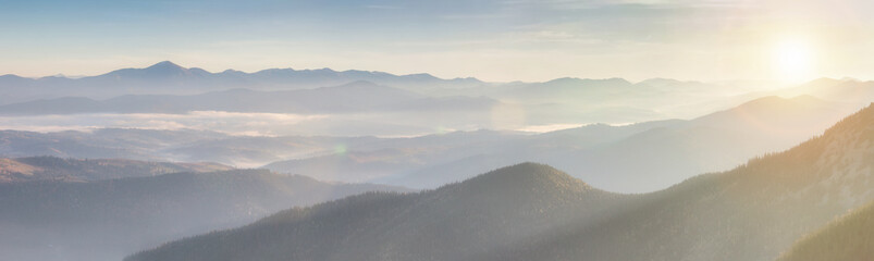 Panorama alpine landscape of the mountain peaks and valleys covered in fog at dawn. Spring ...