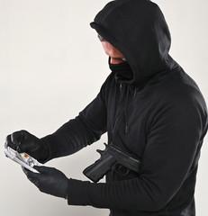 Man in black mask and hoody with a gun and pack of dollars