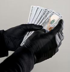 Man in black gloves holding pack of dollars  over gray background
