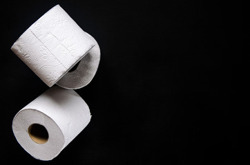 Rolls of white toilet paper lie on a black background