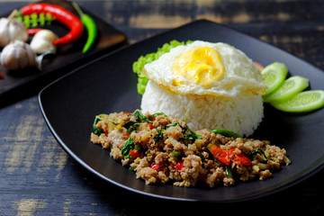 Stir fried Thai basil with minced pork and a fried egg on dark background