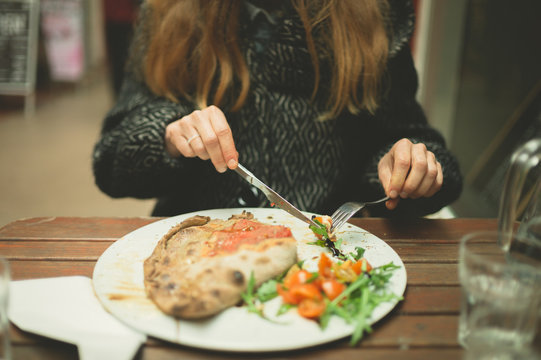 Young woman eating calzone pizza in the winter