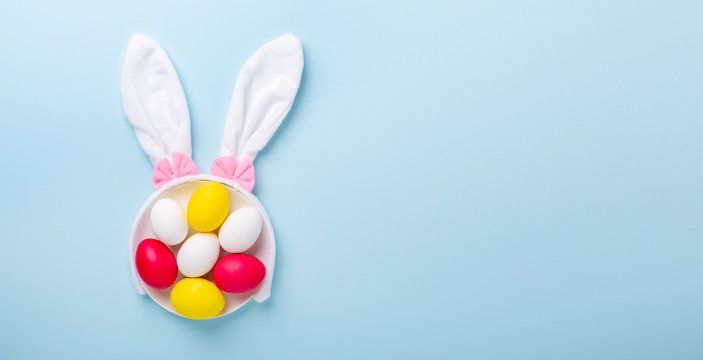 Creative Easter composition. Easter eggs and bunny ears on blue background. Copy space