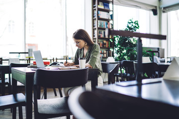 Studios woman writing in notebook in library
