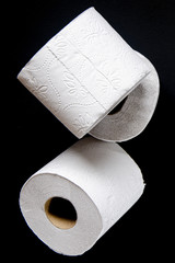 Rolls of white toilet paper lie on a black background
