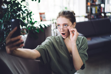 Smart student with excited face taking selfie in library