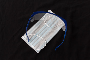 Close up shot of medical accessories on warm background. Plastic glasses and face mask supply during corona virus outbreak in Europe. Covid-19 concept, international crisis.