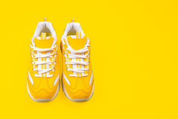 Yellow female sneakers on yellow background.
