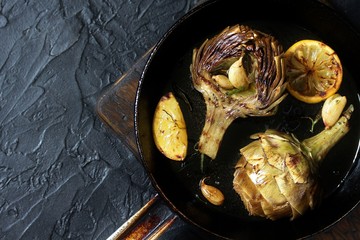 grilled artichoke with lemon in a pan.  Flatlay.  copy space. top view