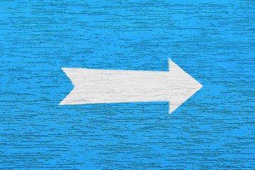 Arrow on a blue textured surface. A white arrow pointer is drawn on the plastered wall of the...