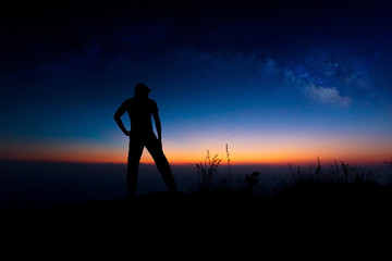 Landscape with Milky Way. Night sky with stars and silhouette of a standing happy man on the...