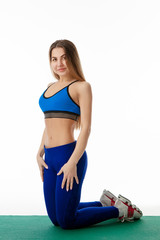 a girl in sports clothes on a Mat sports poses on a white background