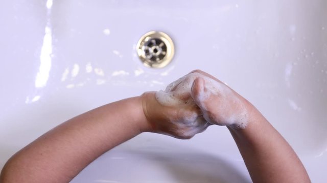 overhead view of a unrecognizable child boy washing their hands in a sink with soap
