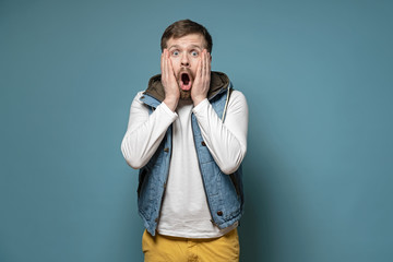 Handsome, bearded man is surprised, he does not believe what he saw, put hands on cheeks and in...