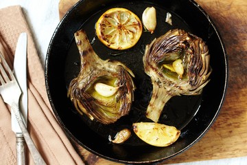 grilled artichoke with lemon in a pan.  Flatlay.  copy space. top view