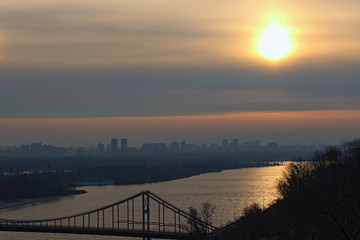 Astonishing landscape view of Dnipro River with the Pedestrian Bridge during spring colorful sunrise. Buildings with morning mist in the background. Saint Vladimir Hill. Kyiv, Ukraine