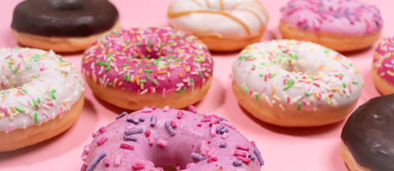 Obraz na płótnie Canvas Web banner. Close-up traditional doughnuts with glaze on trendy pink background.