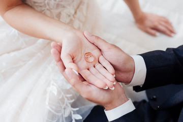 Close-up of groom's hand and bride's hand holding wedding rings