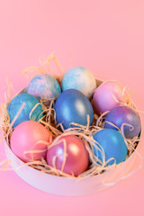 Fototapeta na wymiar Still life with easter decorated eggs in a box on a pink background.