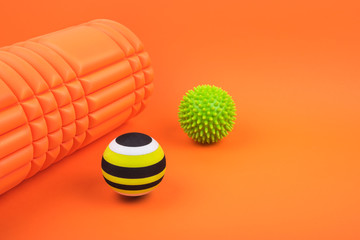 Set of two myofascial release and massage balls, bumpy foam massage roller for trigger points over orange background.