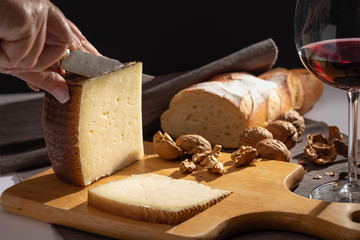 Manchego cheese and nuts on wooden table.
