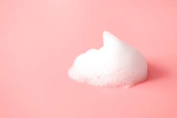 White foam snear from soap, shampoo or cleanser on pink background with selective focus. Close-up, macro - obrazy, fototapety, plakaty