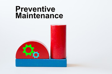 Silhouette of a factory building with chimney made of toy blocks and gear symbols on the blocks. The heading is against a white background: Preventive Maintenance