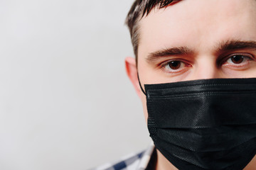 man in a shirt in a black medical mask on a gray background