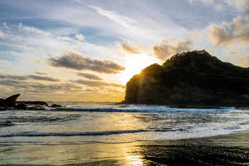 Sunsetting and waves rushing on the beach. Bethels Beach, Auckland, New Zealand